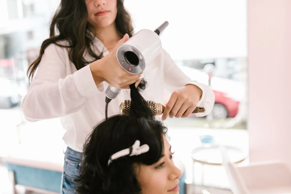 A stylist blow-drying a client's hair